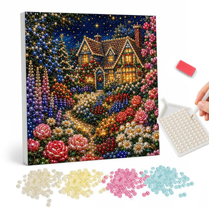 Red Rose Cottage After Dark pearl painting – Glowing cottage at night with red and pink roses and purple spires filling the garden in front