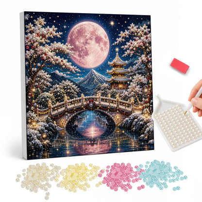 Arched Bridge Under a Pink Moon pearl painting – Large pink full moon above an arched bridge, a pagoda and a mountain, reflected in a lake with frosted trees