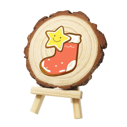 Smiling Star in a Red Stocking paint by numbers wood slice – Smiling yellow star poking out of a red stocking with a white cuff and white stitching, painted on a pine slice on a small easel