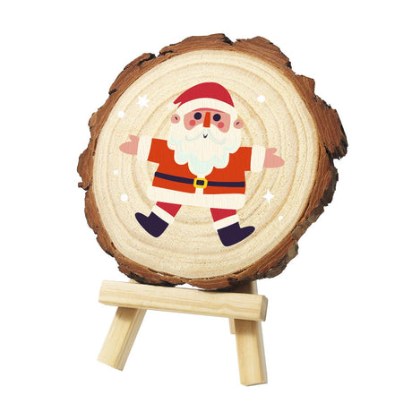 Jumping-Jack Santa in the Snow paint by numbers wood slice – Rosy-cheeked Santa in a red coat and black belt, arms and legs flung wide, with snowflakes around, painted on a pine slice on a small easel