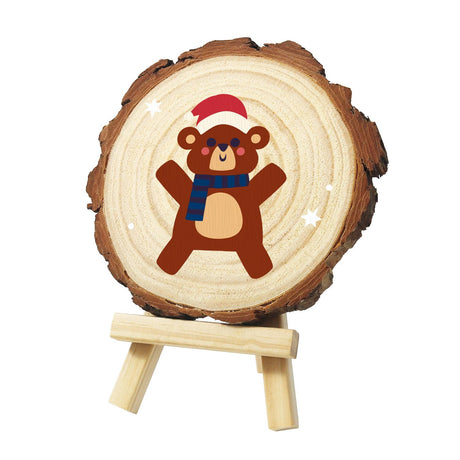 Cuddly Bear in a Navy Scarf paint by numbers wood slice – Brown bear with rosy cheeks in a red Santa hat and navy striped scarf, arms and legs spread wide, painted on a pine slice on a small easel