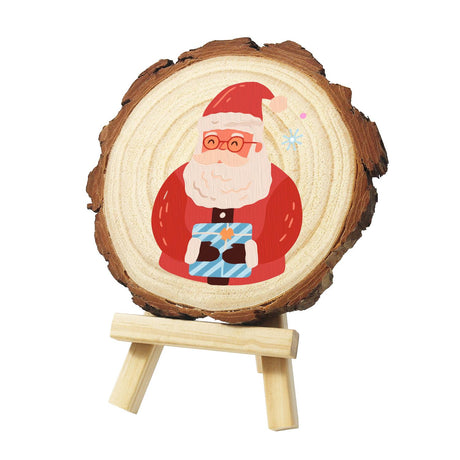 Bespectacled Santa with a Gift paint by numbers wood slice – Santa Claus with round glasses and a big white beard, holding a blue striped gift box, painted on a pine slice on a small easel